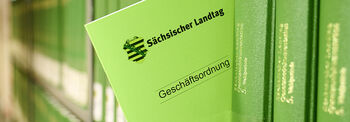 Zwischen grünen Büchern steckt die aktuelle Geschäftsordnung des Parlaments.