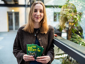 Praktikantin Madita Markgraf lächelt in die Kamera und hält Tierpostkarten in den Händen.