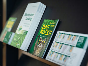 Auf einem offenen Regal liegen diverse Broschüren und Magazine.
