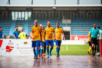 Fußballspieler verlassen den Platz im strömenden Regen.
