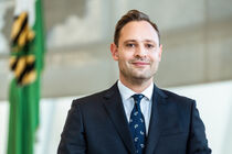 Landtagspräsident Alexander Dierks im Plenarsaal vor der Sachsenflagge