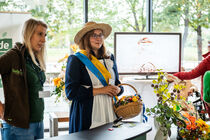 Das Sebnitzer Blumenmädchen steht mit blumengefülltem Korb an ihrem Stand.