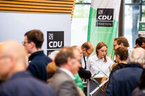 Am Stand der CDU stehen Menschen , die sich mit den stellvertretenden Abgeordneten der Partei unterhalten.