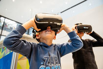 Zwei Kinder haben die VR-Brillen auf und erleben den Landtag durch diese Brille.