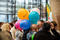 Ein Mann trägt einen Luftballonstrauß mit sich durch die Menge.