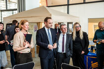 Der Landtagspräsident, die Projektleiterin der Spurensuche und eine Abgeordnete stehen interessiert vor einem Stand