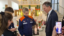 Ein Mädchen der Jugendfeuerwehr übergibt das Friedenslicht an Landtagspräsident Dr. Matthias Rößler im Altbaufoyer