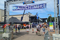 Viele Menschen laufen auf dem Vorplatz zwischen Einsatzfahrzeugen auf der Blaulichtmeile umher.