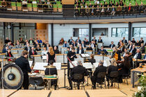 Dirigent mit Musikern und Publikum im Plenarsaal.
