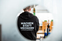 Ein Mann schaut in den Plenarsaal und auf seinem Pullover ist der Spruch 
