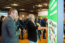 Gäste schauen sich Tafeln der Ausstellung im Bürgerfoyer an.
